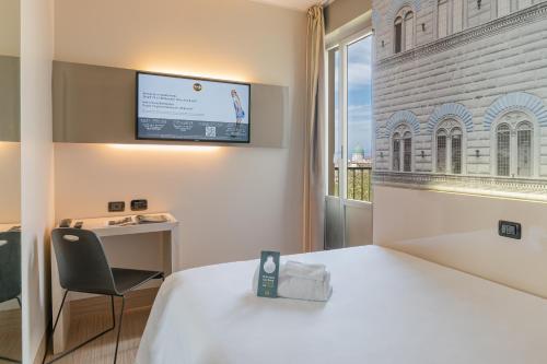 a hotel room with a bed and a chair and a window at B&B Hotel Firenze City Center in Florence