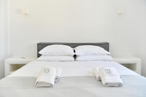 a white bed with two white towels on it at 21 luxury apartments in Naousa