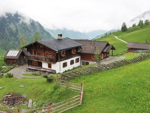 a large wooden house on a hill with a green field at Farmhouse with views over the valley in Rauris