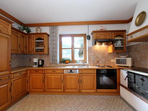 eine große Küche mit Holzschränken und einem Fenster in der Unterkunft Serene Cottage in Neukirchen am Gro venediger in Neukirchen am Großvenediger