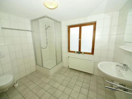 a white bathroom with a shower and a sink at Spacious Holiday Home in Kappl with Terrace in Kappl