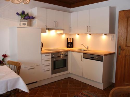 a kitchen with white cabinets and a sink at Apartment with Garden Garden Furniture BBQ in Taxenbach