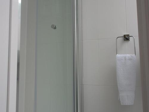 a shower with a glass door and a towel at The Swan Hotel in Milton Keynes