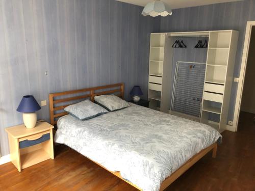 une chambre avec un lit et une table de chevet avec une lampe dans l'établissement "Les Mouettes" Maison de pêcheur en centre ville, à Saint-Vaast-la-Hougue