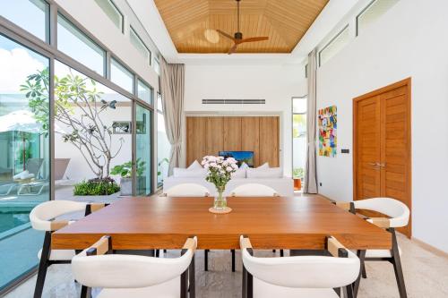 a dining room with a wooden table and white chairs at Shambhala Grand Villa - Private Pool Villas by Escape Villas - Top Choice - Guest Favorite - Best Location in Bang Tao Beach