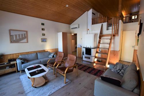 a living room with a couch and a kitchen with a staircase at Pyhtään Vuokramökit in Tuuski