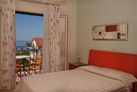 liocharis villas في لورداهاتا: غرفة نوم مع سرير وإطلالة على المحيط