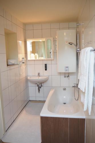 La salle de bains blanche est pourvue d'un lavabo et d'une baignoire. dans l'établissement Ferienwohnung Fürstenbrunn, à Grödig