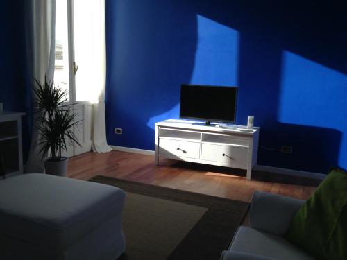 sala de estar con pared azul y TV en Casa Luthi, en Siracusa