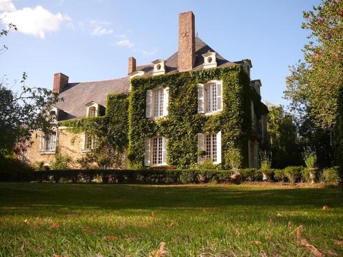 a house covered in ivy on a lawn at La Marronniere in Cheffes-sur-Sarthe