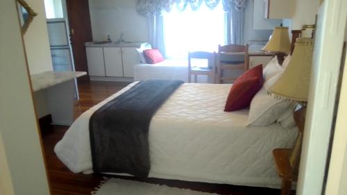 a bedroom with a bed with white sheets and red pillows at Access Guest House in Summerstrand
