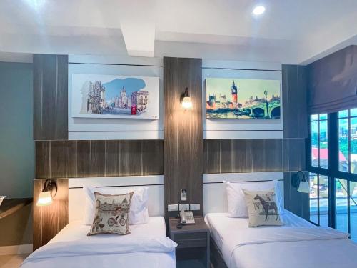 una camera d'albergo con due letti e foto appese alla parete di We Resident Hotel a Hat Yai
