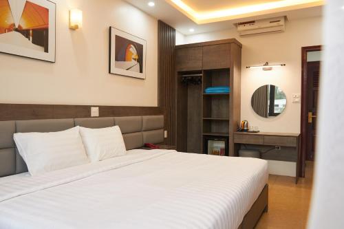 a bedroom with a large white bed and a mirror at Van Nam Hotel in Ha Long