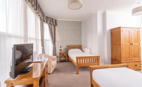 a bedroom with two beds and a tv in a room at Lauriston Hotel in Weston-super-Mare