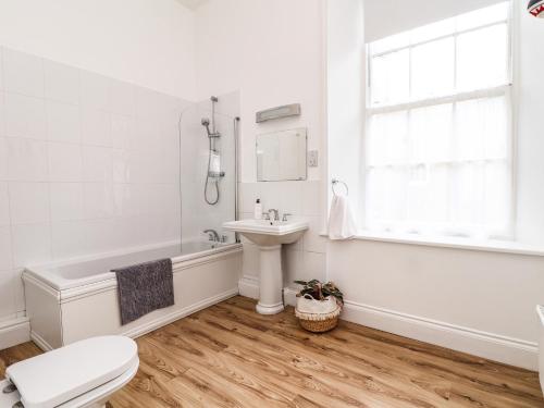 a white bathroom with a tub sink and a toilet at 1 Regents Mews in Penzance