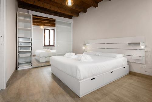 een witte slaapkamer met een groot wit bed en een spiegel bij Flats4Rent Irene in Verona