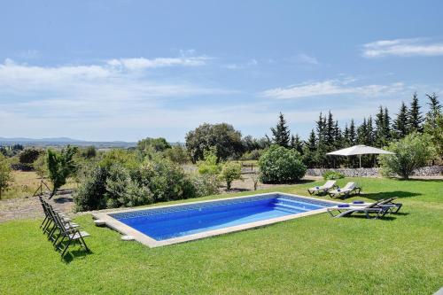 a swimming pool in the middle of a lawn with chairs at Villa Aubons by Slow Villas in Crestatx