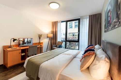 a hotel room with a bed and a desk and a window at KONCEPT HOTEL Benedikt in Siegburg