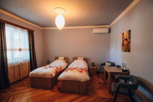 Habitación con 2 camas, mesa y ventana en Bed & Breakfast 3 Gs en Goghtʼ