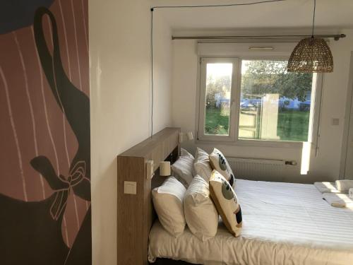 a bedroom with a bed with pillows and a window at Hôtel Heod - Binic - Saint-Quay-Portrieux in Étables-sur-Mer
