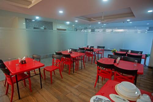 uma sala de jantar com mesas e cadeiras vermelhas em Grey House Inn em Guwahati
