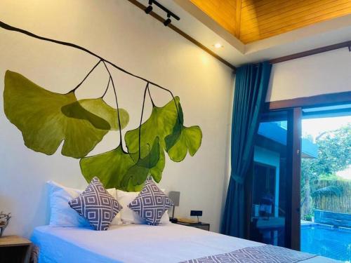 ein Schlafzimmer mit einem Bett mit Blättern an der Wand in der Unterkunft 5 Bedroom Private Pool Villa in Krabi