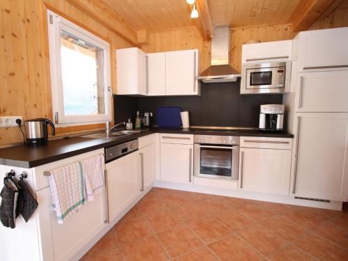 une cuisine avec des placards blancs et un comptoir dans l'établissement Wooden chalet in Hohentauern Styria with sauna, à Hohentauern