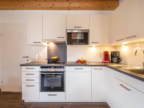 a kitchen with white cabinets and a stove top oven at Chalet in Koetschach-Mauthen in Carinthia in Kötschach