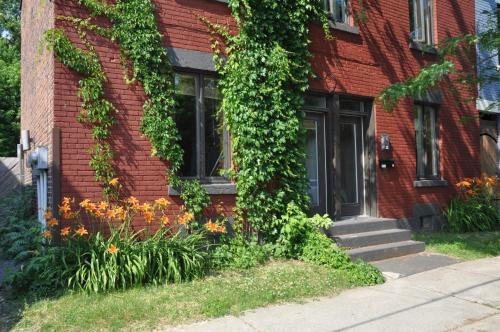 a red brick house with a black door and flowers at Le Tierra del Fuego by HomeInMontreal in Montréal