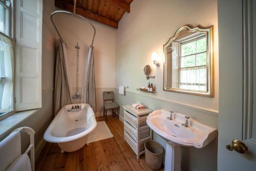 uma casa de banho com 2 lavatórios, uma banheira e um espelho. em Bartholomeus Klip Farmhouse em Hermon