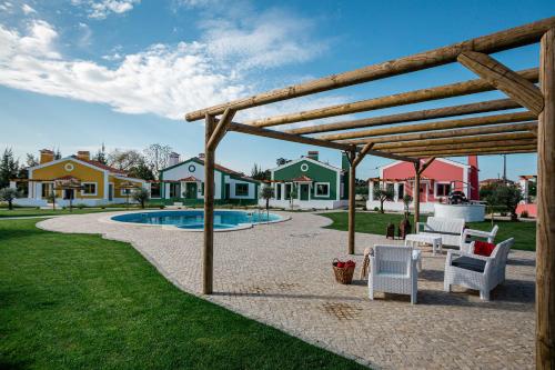 a patio with a wooden pergola next to a pool at QR Casas de Campo in Vale de Santarém
