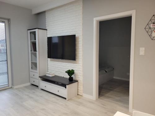 a living room with a television on a brick wall at Apartament Piątka in Płock