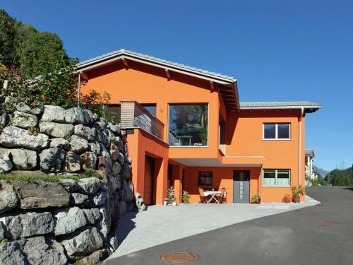 an orange house with a stone wall at Nice apartment at Sonnenkopf in a natural paradise in Dalaas