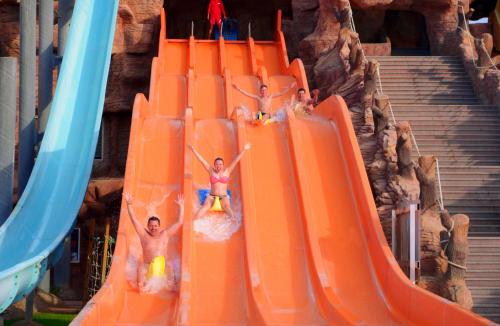 three people on an orange slide at a water park at Pickalbatros Aqua Blu Sharm El Sheikh in Sharm El Sheikh