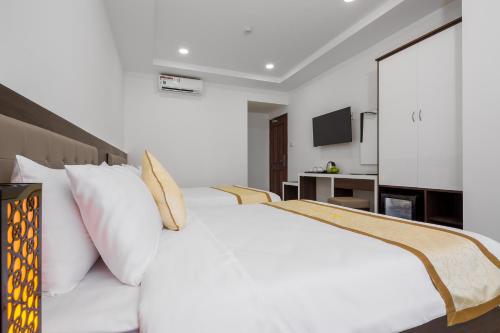 a white bed with white pillows in a bedroom at Phuc Thanh Luxury Hotel by THG in Da Nang