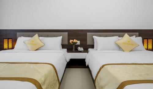 two beds in a hotel room with a table at Phuc Thanh Luxury Hotel by THG in Da Nang