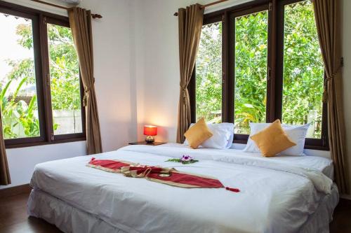 a bedroom with a large white bed with windows at Banburi Villa - 4 Bedroom Private Pool Villa in Krabi town
