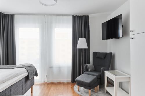 a bedroom with a bed and a chair and a television at Continental Apartment Hotel Knivsta in Knivsta