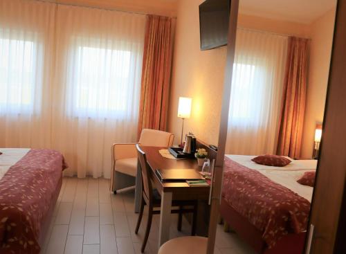 a hotel room with two beds and a desk at Land-gut-Hotel am Ring in Meuspath