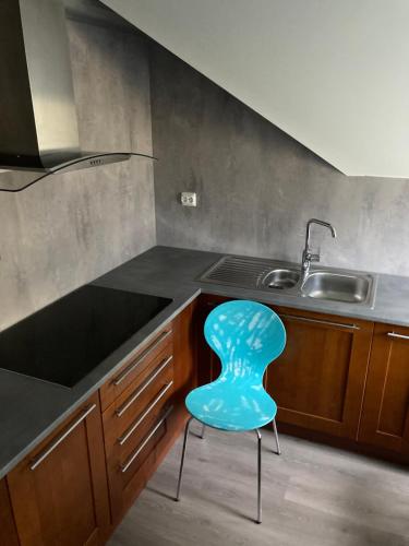 a blue chair sitting in a kitchen next to a sink at Downtown Historical House with Renovated apartments in Ålesund