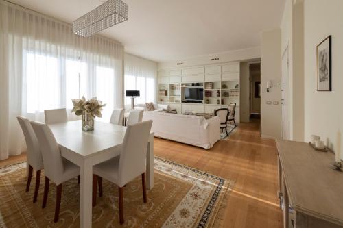 una sala da pranzo e un soggiorno con tavolo e sedie bianchi di Casa Gramsci luxury apartment a Pesaro