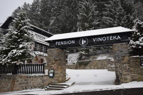 a building with a sign for a ski resort in the snow at Pension St. Moritz in Železná Ruda