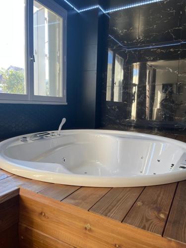 uma grande banheira branca numa casa de banho com paredes azuis em Seasides Paris - Suite Monroe em Le Blanc-Mesnil