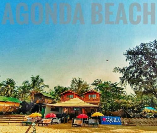 a beach with tables and umbrellas in front of houses at Aquila Boutique Resort Agonda in Canacona