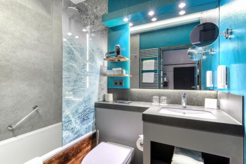 ein Bad mit einem Waschbecken und einem Spiegel in der Unterkunft Unsöld's Factory Hotel in München