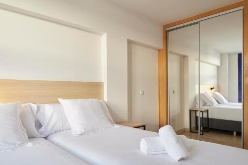 a bedroom with two white beds and a mirror at Iraipe Logroño Hotel in Logroño