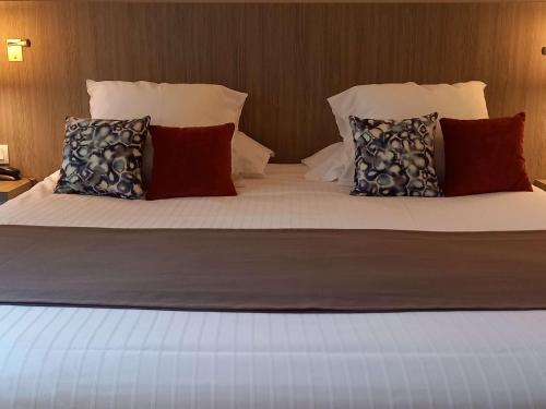 Un dormitorio con una cama con almohadas. en Mercure Dinan Port Le Jerzual, en Dinan