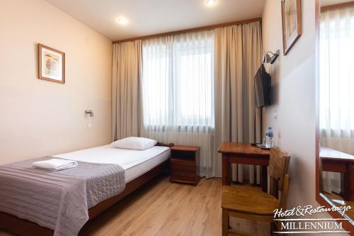 a hotel room with a bed and a desk and a window at Hotel Millennium in Przasnysz