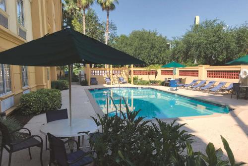 a swimming pool with a table and an umbrella at La Quinta by Wyndham Tampa Brandon Regency Park in Brandon