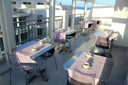 a balcony with tables and chairs with cups on them at Atlantis Lodge in Marsalforn